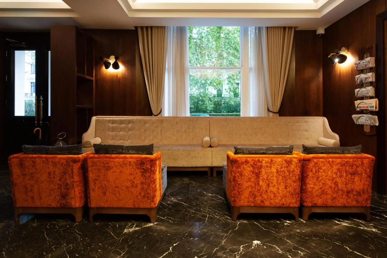 a living room with a couch and orange chairs at Montcalm Chilworth Townhouse in London